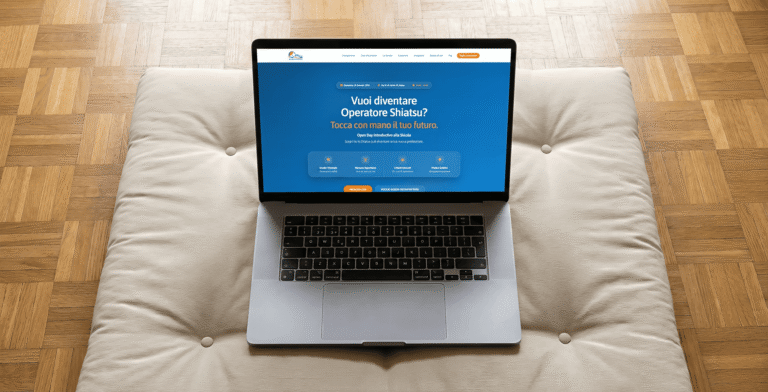 Un laptop aperto appoggiato su un cuscino beige sopra un pavimento in parquet. Lo schermo mostra il mockup di una landing page blu per un Open Day di una scuola di Shiatsu, con il titolo 'Vuoi diventare Operatore Shiatsu? Tocca con mano il tuo futuro' e icone che descrivono i punti di forza del corso.